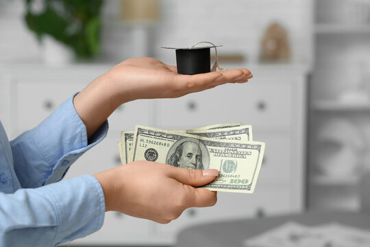 Woman holding money with graduation hat at home, closeup. Student loan concept