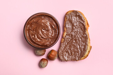 Bread slice with sweet chocolate spread and hazelnuts on pink background