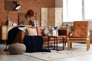 Interior of living room with leather sofa, armchair, folding screen and coffee table