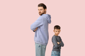 Young father and his little son with crossed arms not looking at each other after squabbling on...