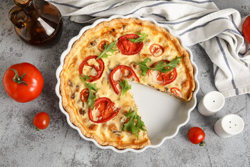 Cut delicious tomato tart with arugula leaves on grey background
