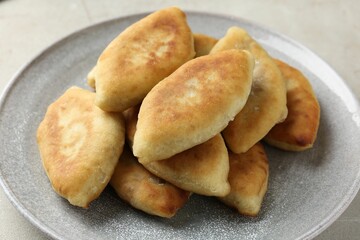 Delicious fried pyrizhky (stuffed pies) on light grey table, closeup