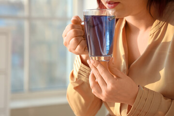 Woman drinking blue tea at home, closeup