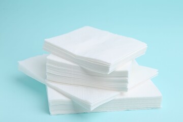 Stack of disposable paper handkerchiefs on light blue background, closeup