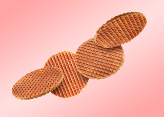 Yummy Dutch waffles (stroopwafels) flying on pink gradient background