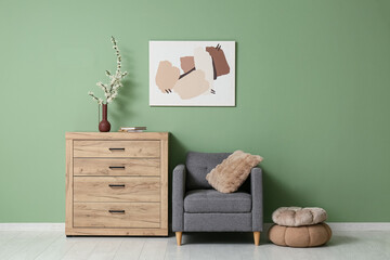 Interior of stylish living room with grey armchair, poufs and blooming tree branches on wooden...