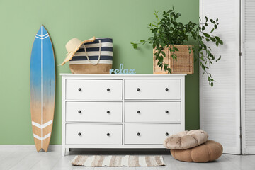 Interior of stylish room with dresser, folding screen and surfboard