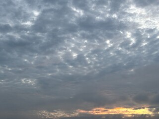 a sky filled with altocumulus clouds with a wavy pattern, creating an interesting texture in the sky. Sunset or faja, golden and grayish blue tones are suitable for backgrounds, atmospheric designs