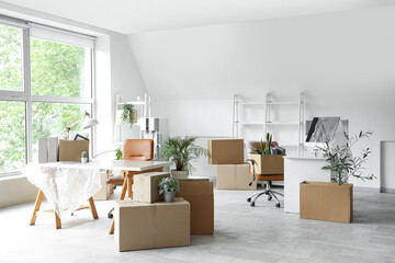 Packed boxes with belongings and furniture in new office on moving day