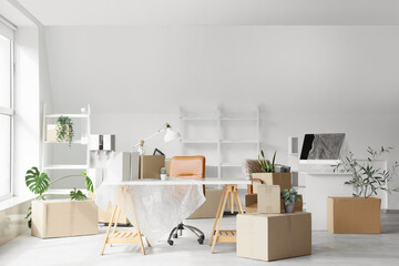 Packed boxes with belongings and furniture in new office on moving day