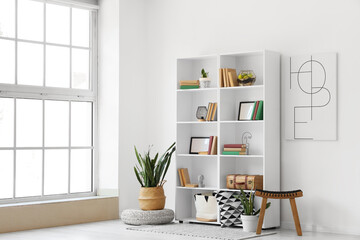 Interior of light room with bookshelf, poster and plants