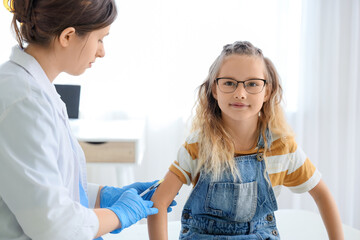Fototapeta premium Little girl receiving vaccine from doctor in clinic
