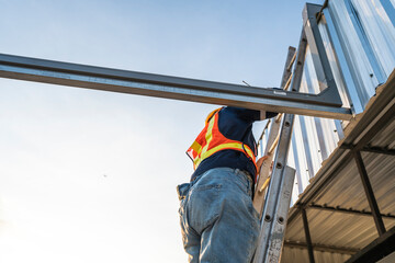A team of technicians with equipment works to inspect the roof structure for the installation of...