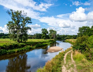 Fototapeta premium Peaceful Riverbank with Lush Greenery and Blue Sky Landscape