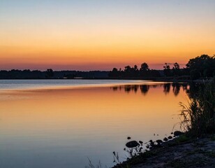 Fototapeta premium Serene Sunset Over Calm Water with Reflective Sky and Silhouettes