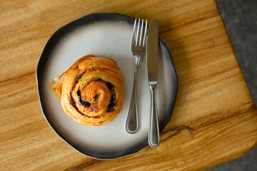 Croissant or Pain aux raisins or danish raisins roll on pottery plate. Roti