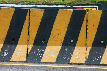 Temporary concrete barrier road divider in yellow and black colors.	
