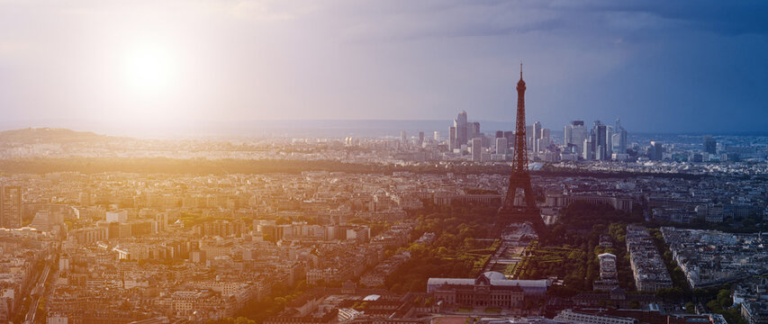 Aerial view of Paris cityscape with Eiffel Tower at sunset, featuring warm sunlight and urban skyline