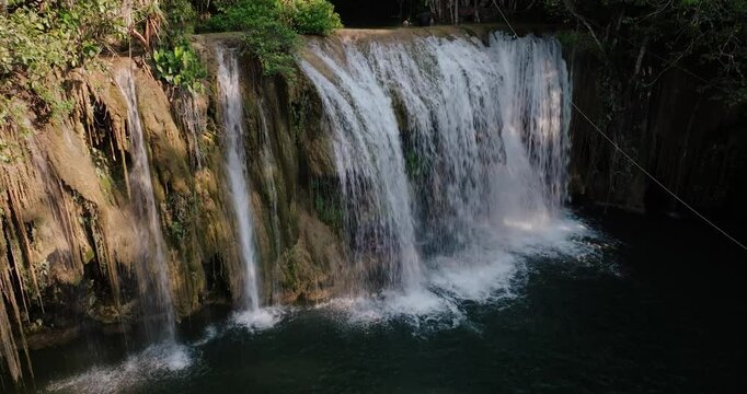 Drone captures stunning close aerial of jungle waterfall plunging over mossy rock into deep dark water in remote Guatemala.