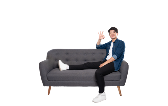 Full body image of young Asian man posing on sofa on PNG background