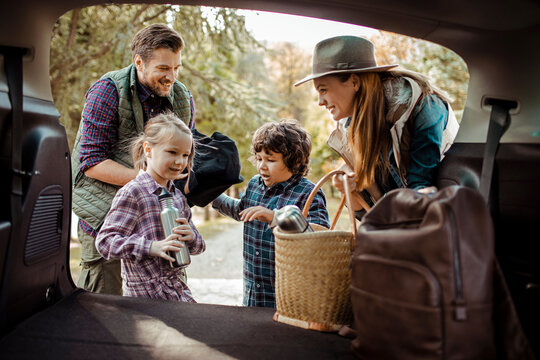 Family packing car trunk together for weekend road trip adventure
