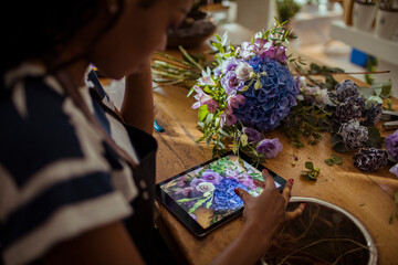 Florist arranging bouquet while referencing design on digital tablet
