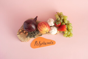 Products containing useful polyphenols in their composition. Grapes, onions, garlic, chocolate and other products in close-up on a pink background top view.