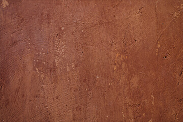 The cement surface is unevenly plastered and painted in dark brown.