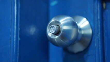 Close-up of a Brushed Steel Door Knob on a Vibrant Blue Door