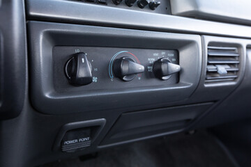 Close-up dashboard details of an older American pickup truck with 4x4 drivetrain. Features include control knobs, radio unit, climate panel, and gauges, all photographed in clean daylight conditions