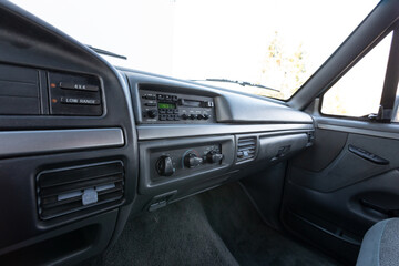 Close-up dashboard details of an older American pickup truck with 4x4 drivetrain. Features include control knobs, radio unit, climate panel, and gauges, all photographed in clean daylight conditions