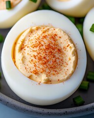 Deviled egg halves sprinkled with paprika, close-up view.