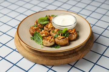 Stuffed mushrooms and sauce on plate on light background