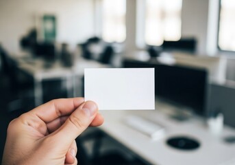 Close-up of a blank white business card held by a hand against a blurred office background