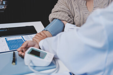 Doctor using sphygmomanometer with stethoscope checking blood pressure to a patient in the hospital.
