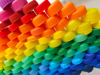 Torre de tapas de plástico de colores para reciclar. Pared formada con tapas de plástico. Colores del arcoíris. Concientización para el cuidado del medioambiente.