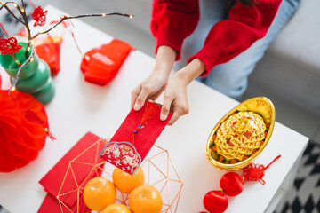 Asian Woman giving red envelope for Lunar New Year celebrations. Hand hold red packet