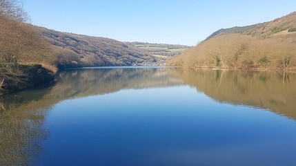 Fototapeta premium Serene lake reflecting hills under a clear sky