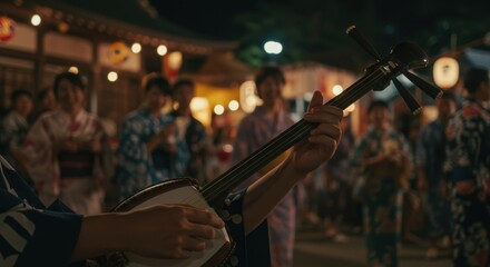 浴衣を着た人々が集まる夜祭りで三味線を演奏する男性