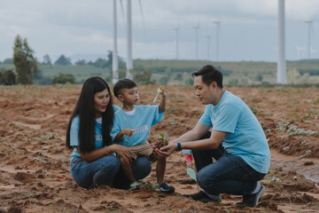 Happy family of father, mother and child are helping each other plant trees on World Warming Day at...