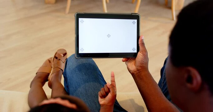 African American, Father and daughter relaxing at home, using tablet for interactive learning, copy