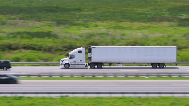 Aerial view of semi-truck driving on busy American interstate freeway. Delivering cargo concept.