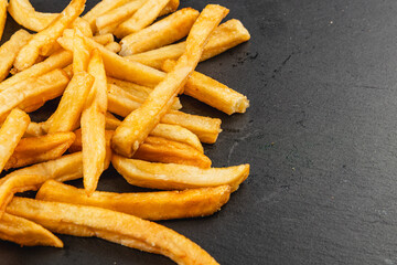 Crispy French fries piled on a dark surface