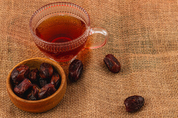 Warm tea and dates on a rustic burlap surface