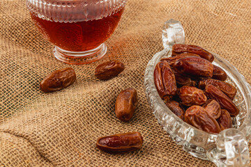 Delicious dates and beverage arranged on burlap background
