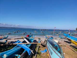 Colorful fishing boats rest under a bright blue sky on a peaceful tropical beach.