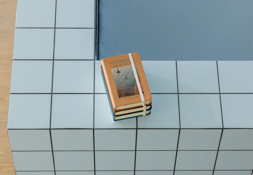 Mockup of Three Stacked Notebooks placed on a tiled surface