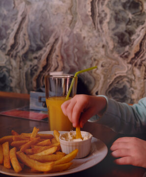 Cuild eating French fries and sour Cream dip, cheese sause with garlic. Crunchy snack, food.  Cafe, fast food restaurant
