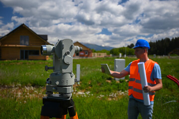 Surveyor working with theodolite and tablet during land surveying for new house construction