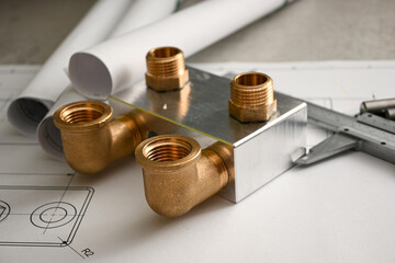 Brass plumbing manifold laying on a water supply system blueprint next to a caliper, showcasing...